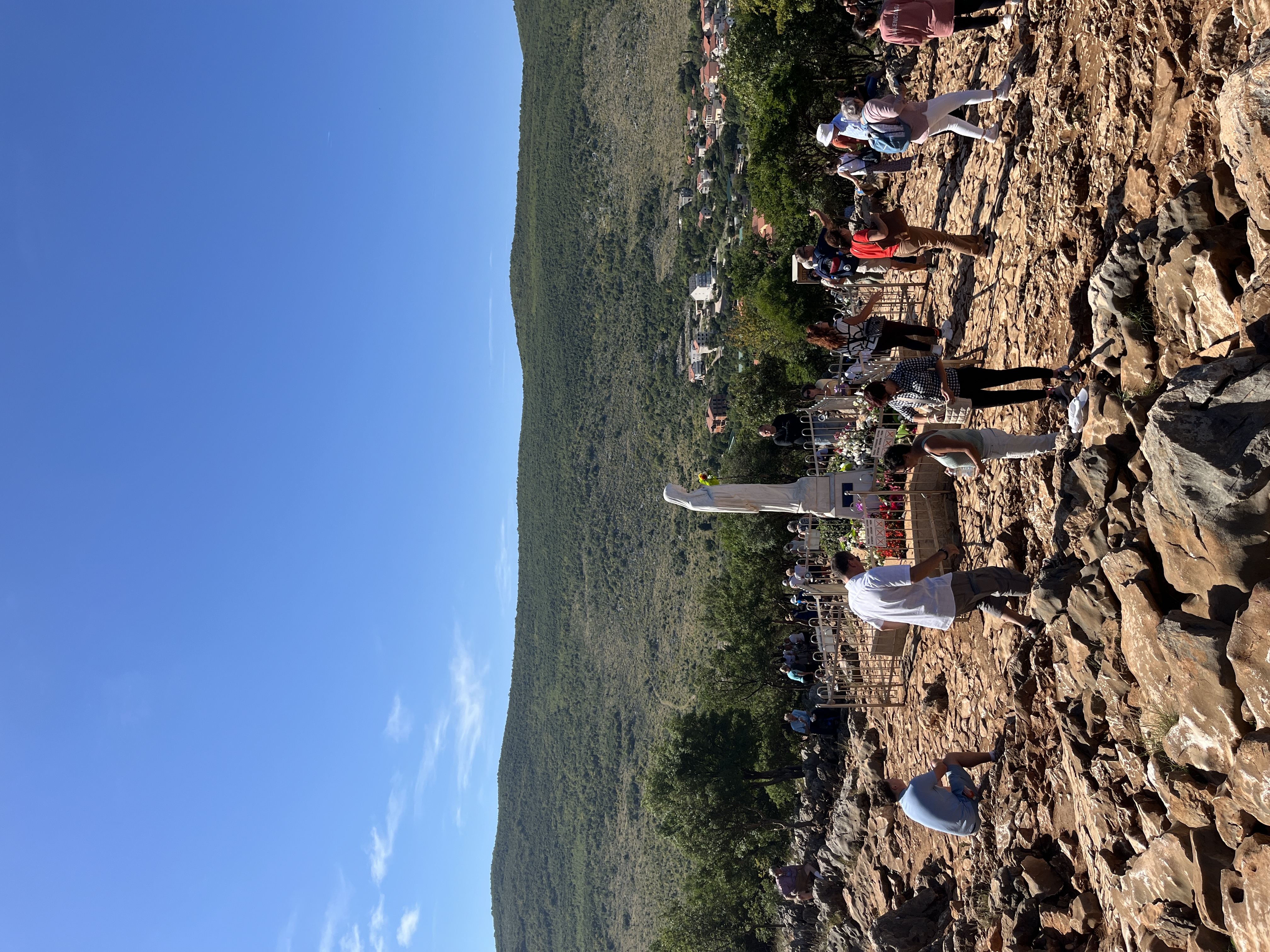 Pilgrims around the white Virgin Mary statue on Apparition Hill, Medjugorje